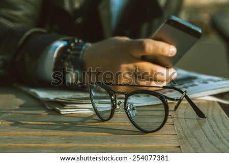 glasses on desk and businessman behind outdoors