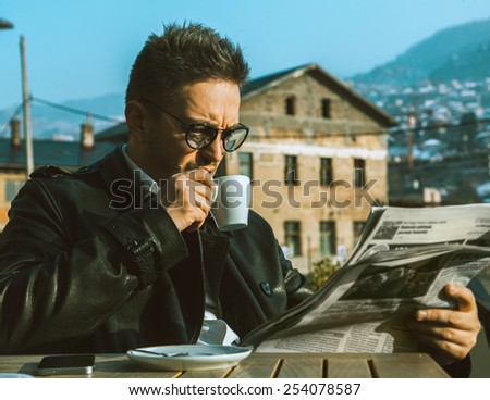 Beautiful adult business man drink coffee and read newspaper outdoors