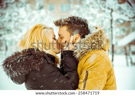 true love. Man and woman happily kissing on the street in the snow. Horizontal color photo