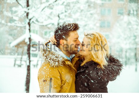Couple hugging and looking into each other\'s eyes in the snow. Horizontal color photo