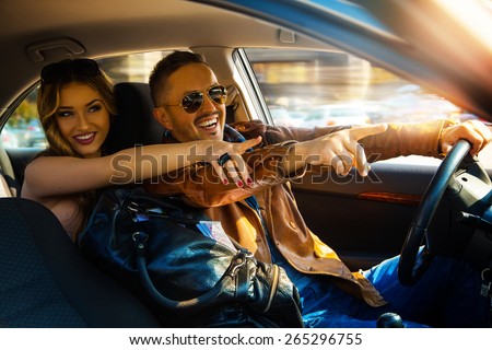Enjoy life fun couple driving car at high speed and point fingers forward. Inside photo