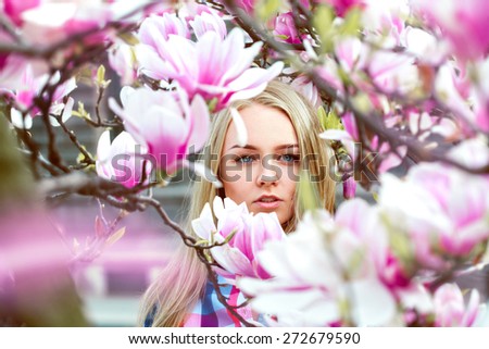 High society blond lady in pink blooming flowers looking at camera outdoors