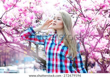 Dreaming young blonde woman looking away with flowers. Spring time