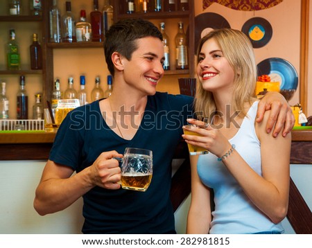 Beauty blonde woman and brunette man smiling and drinking in bar. horizontal photo