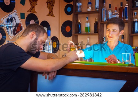 barman gives short cocktail to drunk unshaved man at bar table. horizontal photo