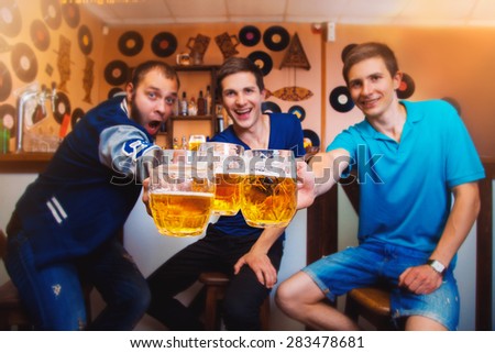 Three cheerful man clink glasses of beer in a bar. horizontal photo