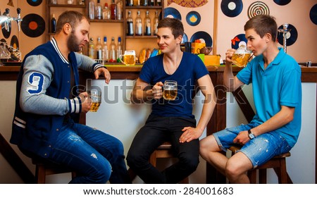 Three men talking and drinking beer in bar. horizontal photo