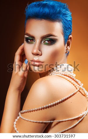 Adorable young woman with blue hair and nails looking at camera. studio shot. orange background