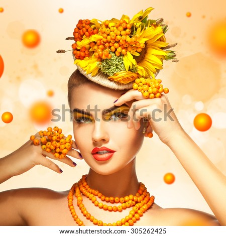 square photo of Beauty fashion model with orange rowan Hair Style. Beautiful Model woman on orange background with rowanberries. Nature Hairstyle. Holiday Makeup and manicure. Make up Vogue Style