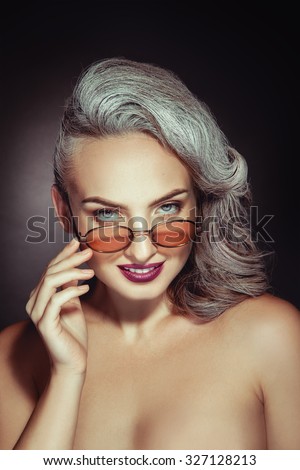 Charming woman with nice makeup and grey hair color in stylish sunglasses in studio