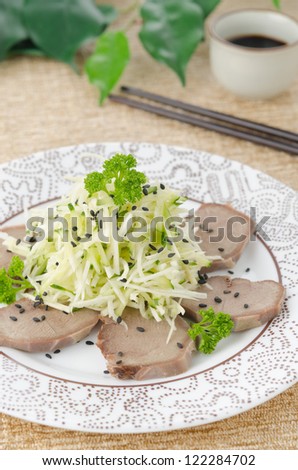 Oriental salad with beef tongue, celery and cucumber on a plate, closeup