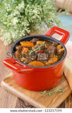 stew of beef with vegetables and prunes in a red cast iron pan