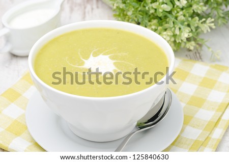 bowl of green pea soup with ginger and cream in a white bowl, closeup, horizontal