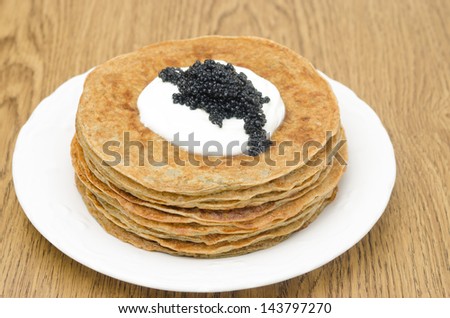 potato pancakes with sour cream and caviar on a wooden table