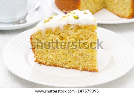 piece of orange cake with Greek yogurt, honey and pistachios on a plate, close-up