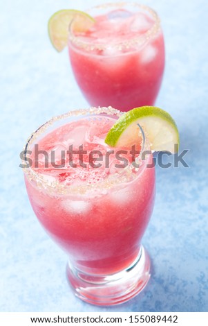 Two glasses of watermelon cocktail with brown sugar and lime, vertical