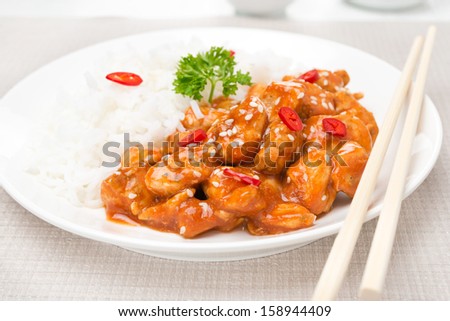 chicken fillet in tomato sauce with sesame seeds, chili and rice, close-up