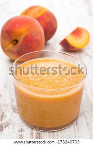 fresh squeezed peach juice and fresh peaches, close-up, vertical