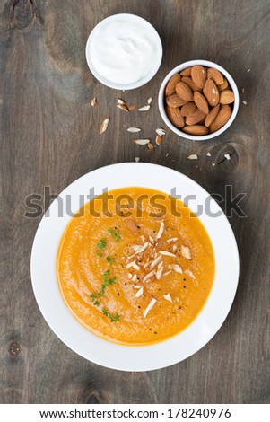 carrot soup with almonds and yogurt, top view, vertical
