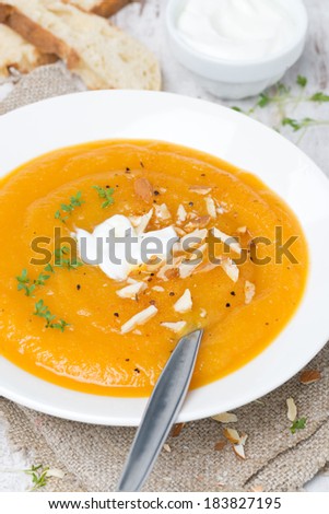 carrot soup with almonds, yogurt and watercress in a plate, top view, vertical