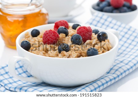 healthy breakfast - oat porridge with berries and honey, close-up