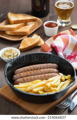 grilled sausages with French fries, toast and beer, vertical, top view