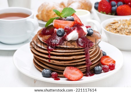 breakfast with pancakes with cream, fruit sauce and fresh berries, close-up, horizontal