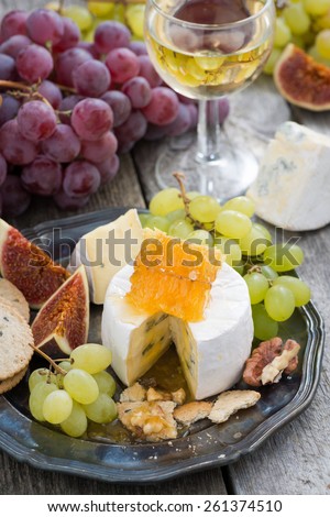 camembert with honey and fruit, snacks and wine on a plate, vertical, top view