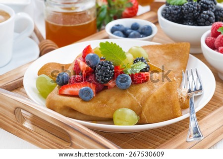 crepes with fresh berries and honey on a plate, close-up