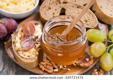 flavored honey, bread with butter and grape on wooden board, top view, horizontal