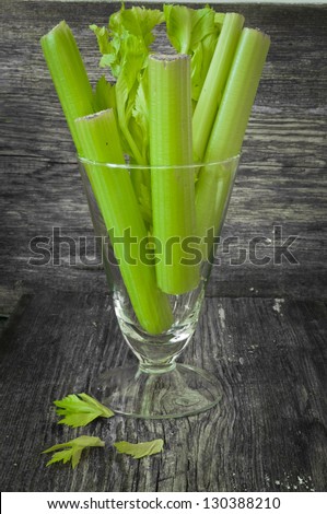 Fresh celery stalks in a glass on a wooden background