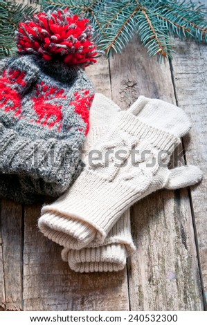 Knitted mittens and knitted hat on a wooden background