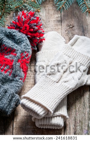 Knitted mittens and knitted hat on a wooden background