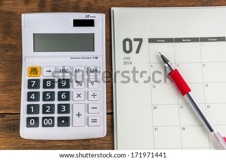 July organizer with calculator & pen: concept for monthly budget.