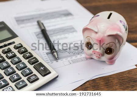 piggy bank with calculator and pen on document background