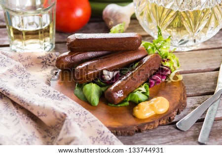 Grilled vegan sausages served on wooden plate