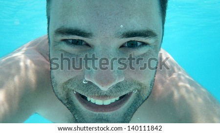 Underwater portrait of man with bubbles in a sea smilingly