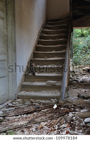 Old wooden staircase and dirty floor in abandoned house interior.