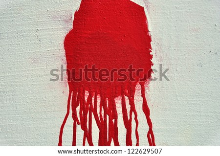 Red paint drips over textured white wall. Abstract background.
