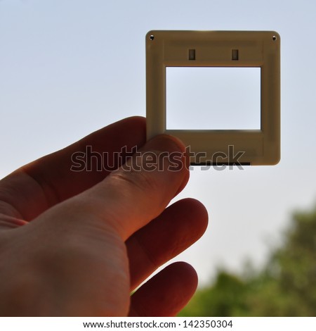Hand with blank photographic slide picture frame. Place your own image or text.