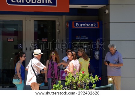 ATHENS, GREECE - JULY 1, 2015: People waiting at atm machine queue at greek bank inform a tourist that there are no capital controls on credit cards issued abroad and no daily cash limit for visitors.