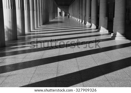 ATHENS, GREECE - OCTOBER 14, 2015: Man walking among the columns of stoa attalos at the ancient agora. Light and shadow abstract architecture black and white.