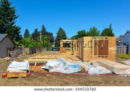 A single family home under construction with tree and blue sky background.