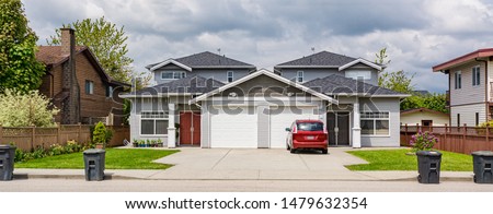 Residential duplex townhouse with red car parked on concret driveway