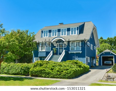 North American family house with detached garage in suburbs of Vancouver. A house on blue sky background.