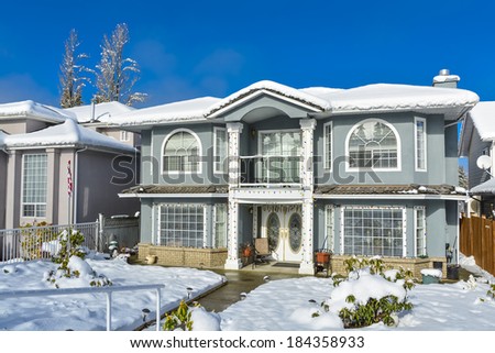 Luxury family house on winter season. Luxury house with handrail on the pathway and blue sky background