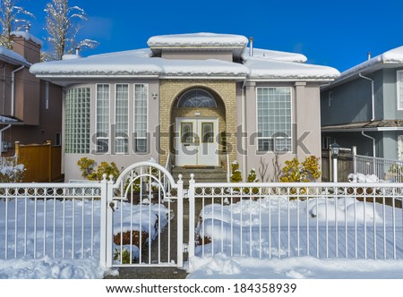 Luxury house with metal fence in front and blue sky background. Luxury family house on winter season with closed entrance gate in front.