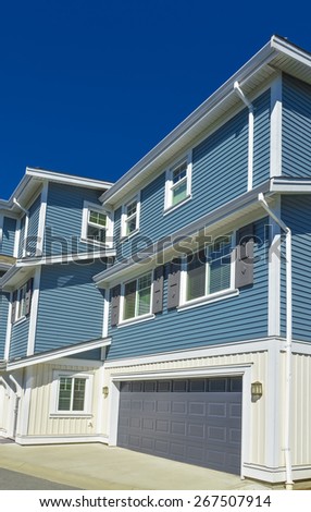 New residential townhouse with concrete driveway on sunny day on blue sky background. British Columbia, Canada.