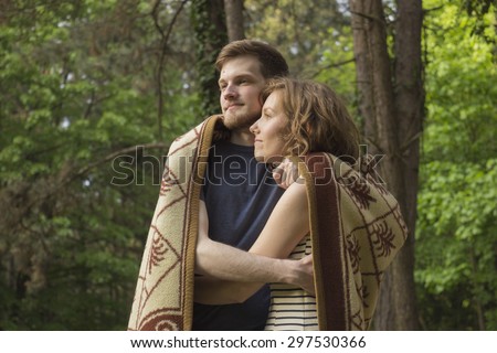girl and boy chill out,in woods, wrapped in blanket.