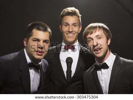 3 male portraits, with suits and bow ties, black background. Similar to tv show poster \